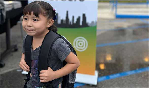 a child walking with a backpack she received from SLYO